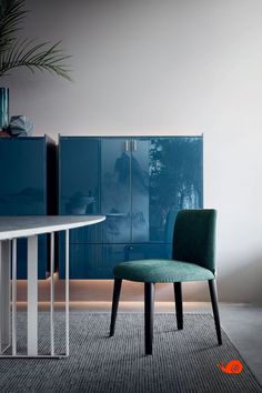 a green chair sitting next to a white table in a room with blue cabinets and drawers