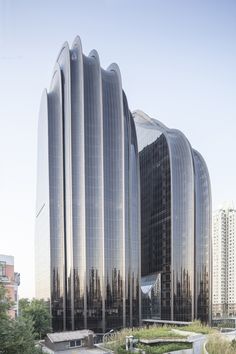 an unusual building in the middle of a city with tall buildings and trees around it