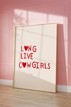 a white framed poster with the words long live cowgirls on it in front of a pink wall