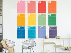 a room with two chairs and a table in front of a wall that has a color chart on it