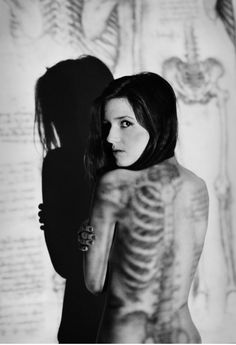 a woman standing in front of a skeleton wall with her back turned to the camera