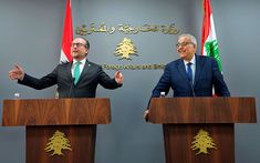 two men standing at podiums in front of flags