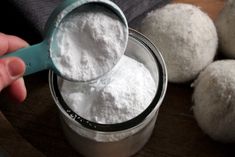 a person scooping sugar out of a jar on top of a wooden table next to some balls