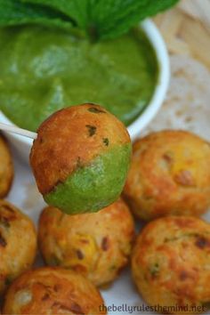 some food is being held up to the camera with a green dipping sauce on top