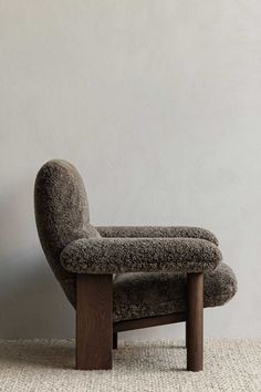 an upholstered chair sits in front of a white wall