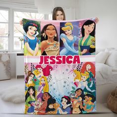 a woman holding up a blanket with princesses on it