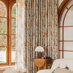 a living room filled with furniture next to a window covered in curtains and drapes