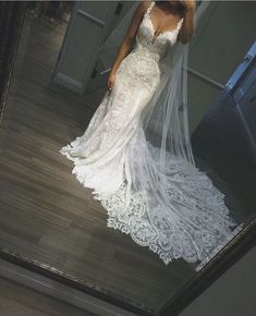 a woman taking a selfie in a mirror wearing a wedding dress with a long veil