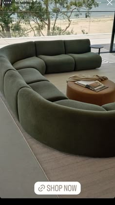 a large green couch sitting on top of a wooden floor next to a glass wall