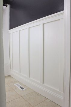 an empty bathroom with white paneling on the walls and tile floor in front of it