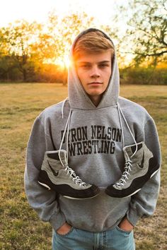 a young man standing in a field wearing a sweatshirt with the words iron nelson wrestling on it