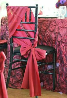 a chair with a red bow tied to it's back sitting in front of a table