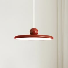 a red light hanging from the ceiling in a room with white walls and flooring