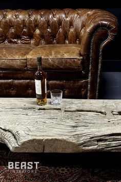 a bottle of wine sitting on top of a wooden table next to a leather couch