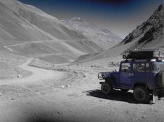 a blue jeep driving down a dirt road