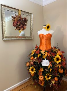 a dress made out of sunflowers and leaves on display in front of a mirror