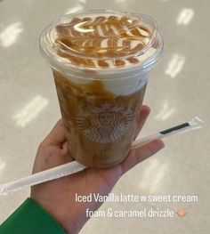 a hand holding a cup of iced vanilla w / sweet cream foam and caramel drizzle