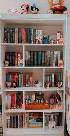 a bookshelf filled with lots of books and stuffed animals on top of it