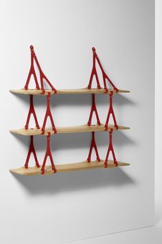 three wooden shelves with red handles on each shelf and one is holding two pairs of scissors