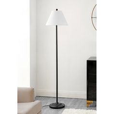 a black floor lamp with a white shade on it in the corner of a room