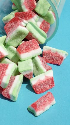 there are many pieces of watermelon on the blue table next to a cup