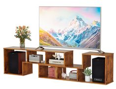 a flat screen tv sitting on top of a wooden shelf next to a vase with flowers