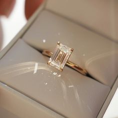 a close up of a ring in a box with a person's hand holding it