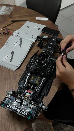 a person is working on an electronic device at a table with other electronics and tools