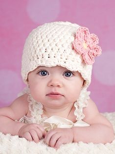 a baby girl wearing a crocheted hat with flowers on it's head