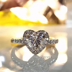 a heart shaped diamond ring on top of a table