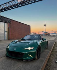 a green sports car is parked on the side of the road in front of a building