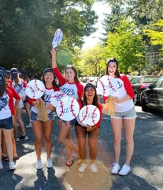 some girls are holding up baseballs in the street