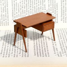 a miniature wooden desk sitting on top of an open book with pages in the background