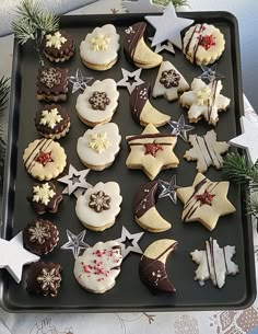 a tray filled with lots of decorated cookies on top of a table next to christmas decorations