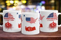 three coffee mugs with flags and roots on them sitting on a table in front of a blurry background