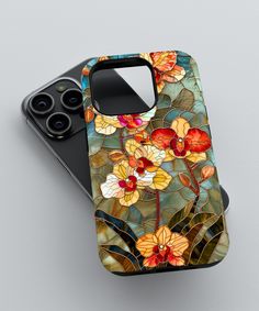 an iphone case with flowers and leaves painted on the front, sitting on a gray surface