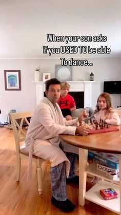 a man sitting at a table with two children playing chess