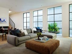 a living room filled with lots of furniture next to tall windows and a coffee table