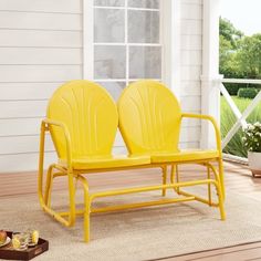 two yellow chairs sitting next to each other on top of a wooden floor in front of a white house