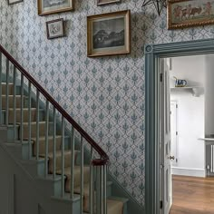 a staircase with pictures on the wall next to it and framed photos above them, along with an open door