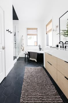 a bathroom with black and white tile flooring next to a bathtub in the corner