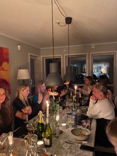 a group of people sitting at a table with wine bottles and candles in front of them