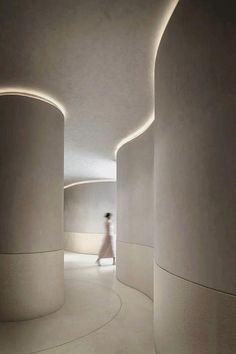 a person walking down a long white hallway with circular lights on the ceiling and walls