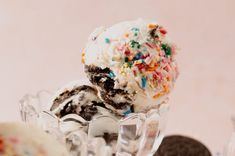 an ice cream sundae with sprinkles and chocolate cookies on the side