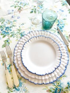 there is a white plate with blue trim on it next to silverware and glasses