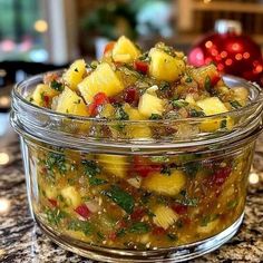 a glass bowl filled with pineapple salsa sitting on top of a counter next to a christmas ornament