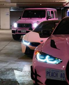 three pink sports cars are parked in a parking garage with their lights turned on and the hoods down