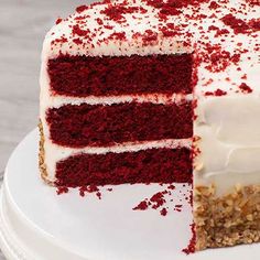 a red velvet layer cake with white frosting and sprinkles on top