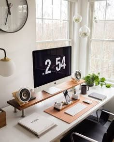 a desk with a computer and speakers on it in front of a large window that reads 2 54