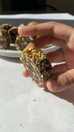 a person holding up a piece of food on a plate next to other pieces of food